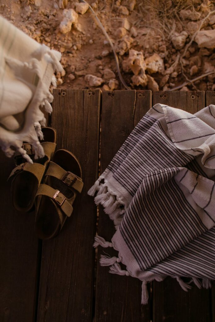 textiles and sandals on wooden surface in daytime